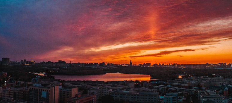 A vibrant sunset over a city skyline, with neon lights reflecting on the buildings, evoking a retro-futuristic atmosphere.