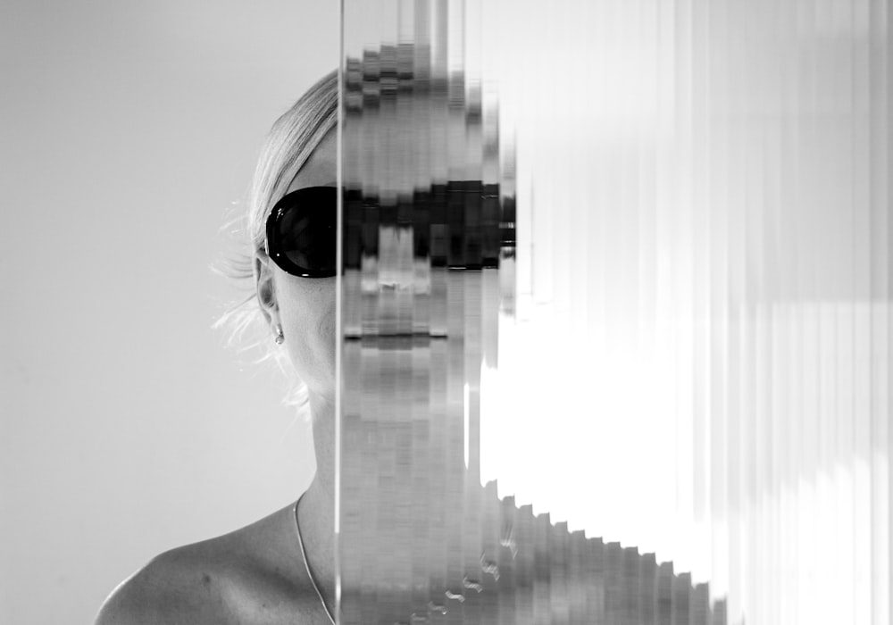 woman wearing sunglasses standing behind glass wall