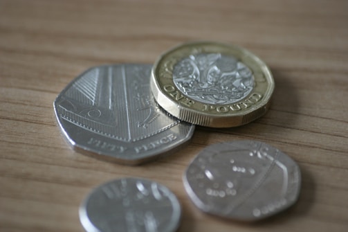 Stack of British pound notes next to a calculator and glasses.