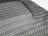 A detailed black mesh material with intricate patterns is laid out, displaying a grid of interlocking loops and open spaces. The texture appears flexible and lightweight, with subtle shadows adding depth.