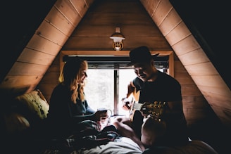man playing guitar facing woman