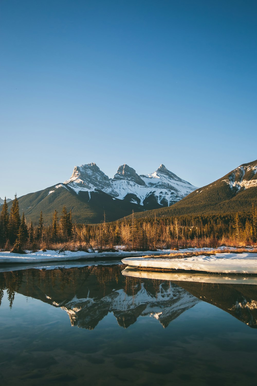 body of water viewing mountain under blue and white sky during daytime