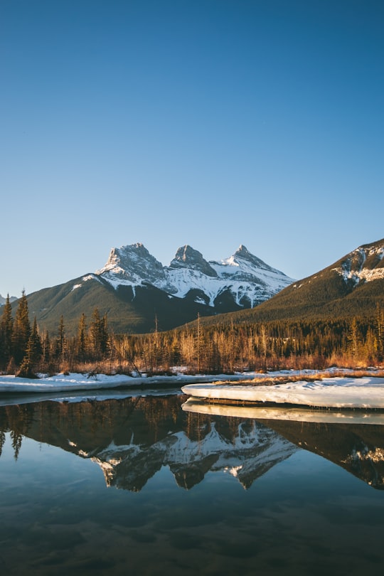 body of water viewing mountain under blue and white sky during daytime in The Three Sisters Canada