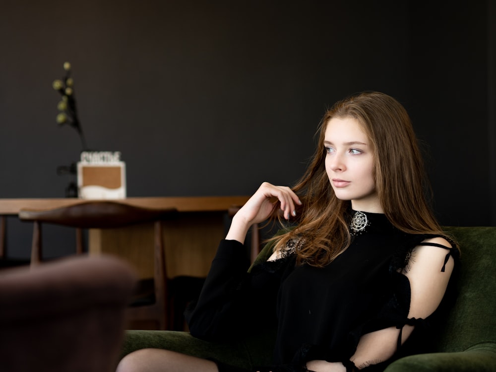 woman in black long-sleeved top sitting on green armchair