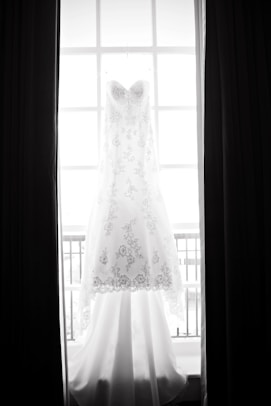 white floral wedding gown beside window