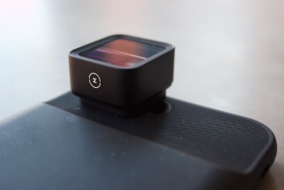 A close-up of a sleek, dark olive metal camera accessory crafted by metarc, resting on a wooden table.