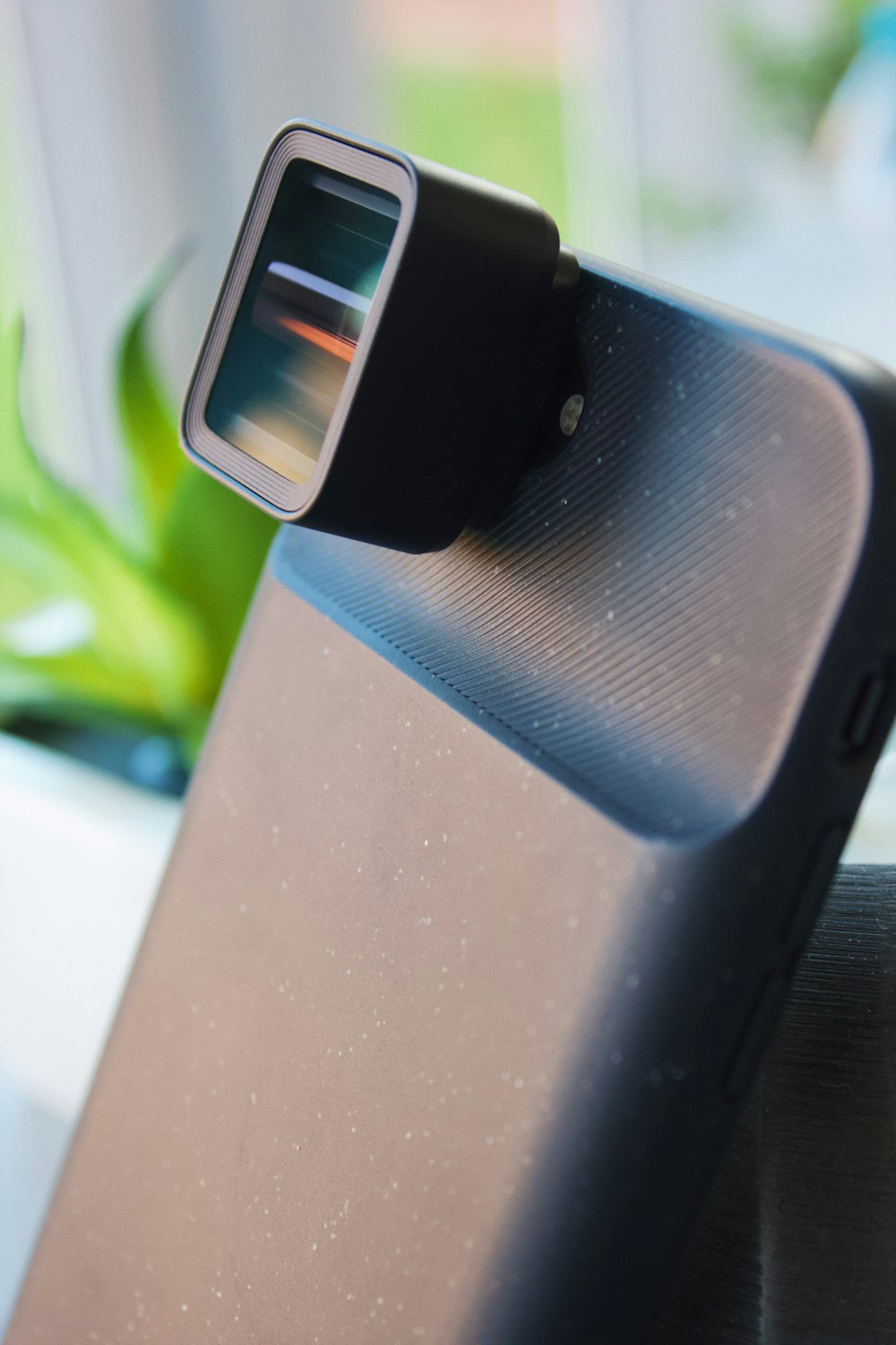 a close up of a speaker with a plant in the background