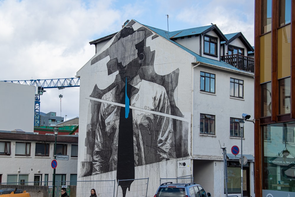 man wearing shirt and necktie mural on building near buildings during day