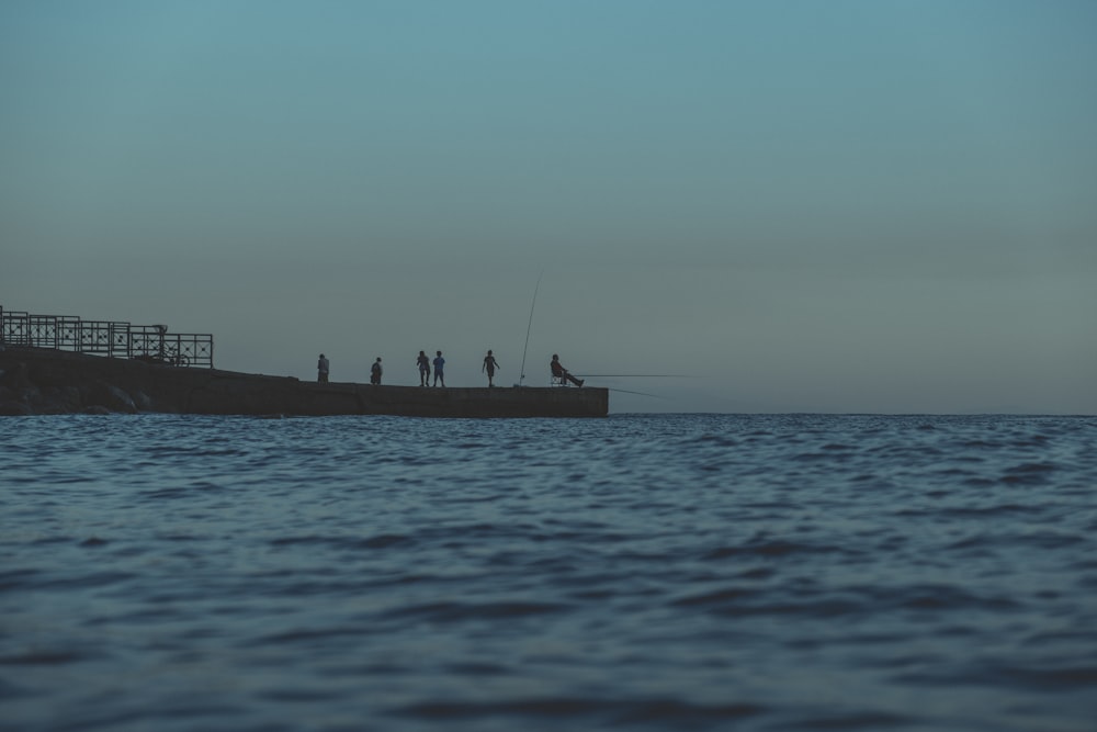 people standing beside body of water