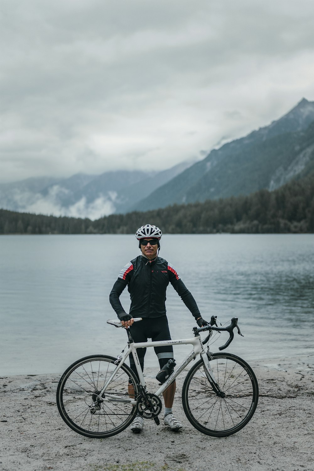 a man standing next to a bike on a beach