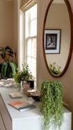 oval brown framed wall mirror beside window