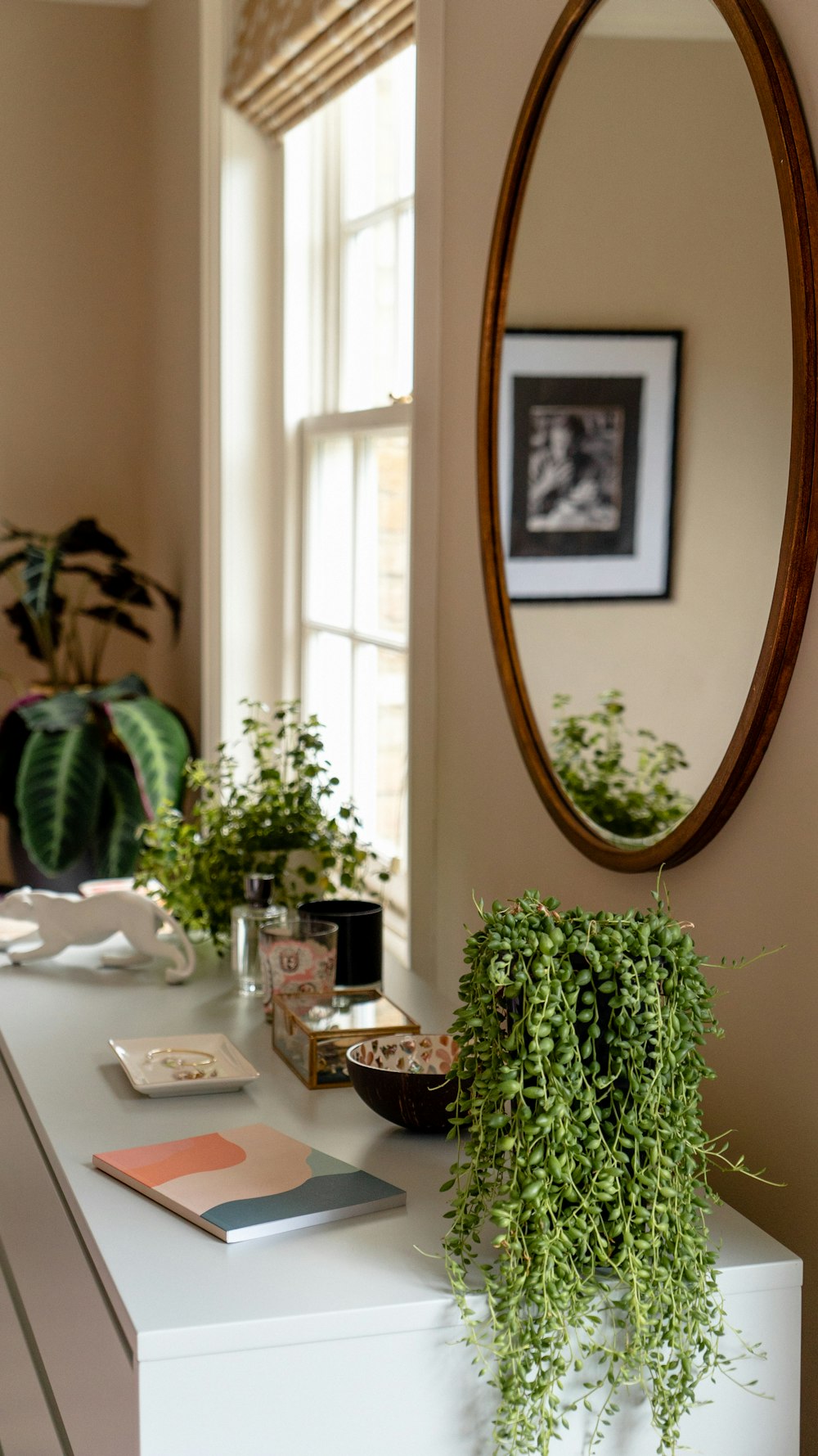 oval brown framed wall mirror beside window