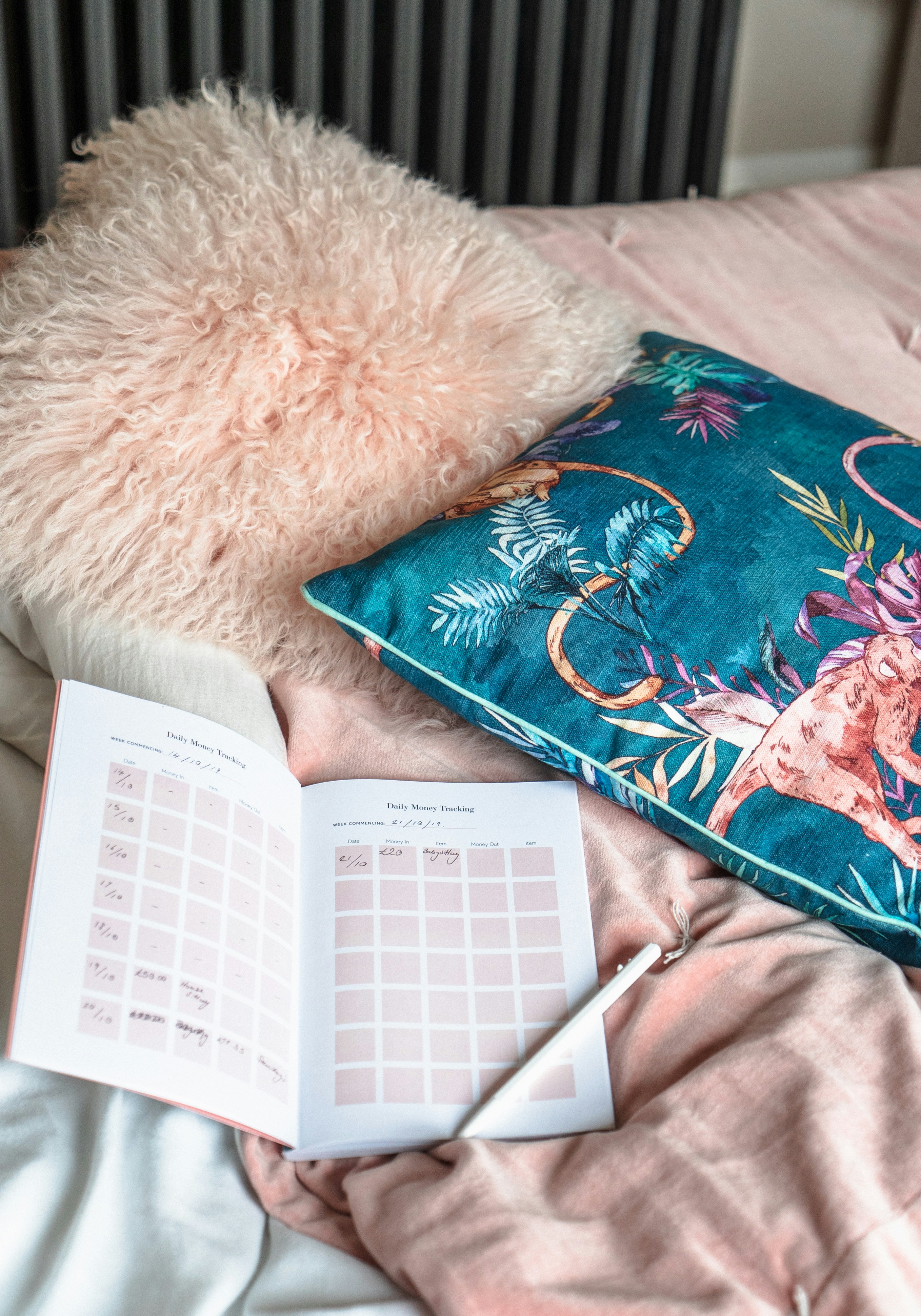 stylo au-dessus d’un livre à côté des coussins dans le lit