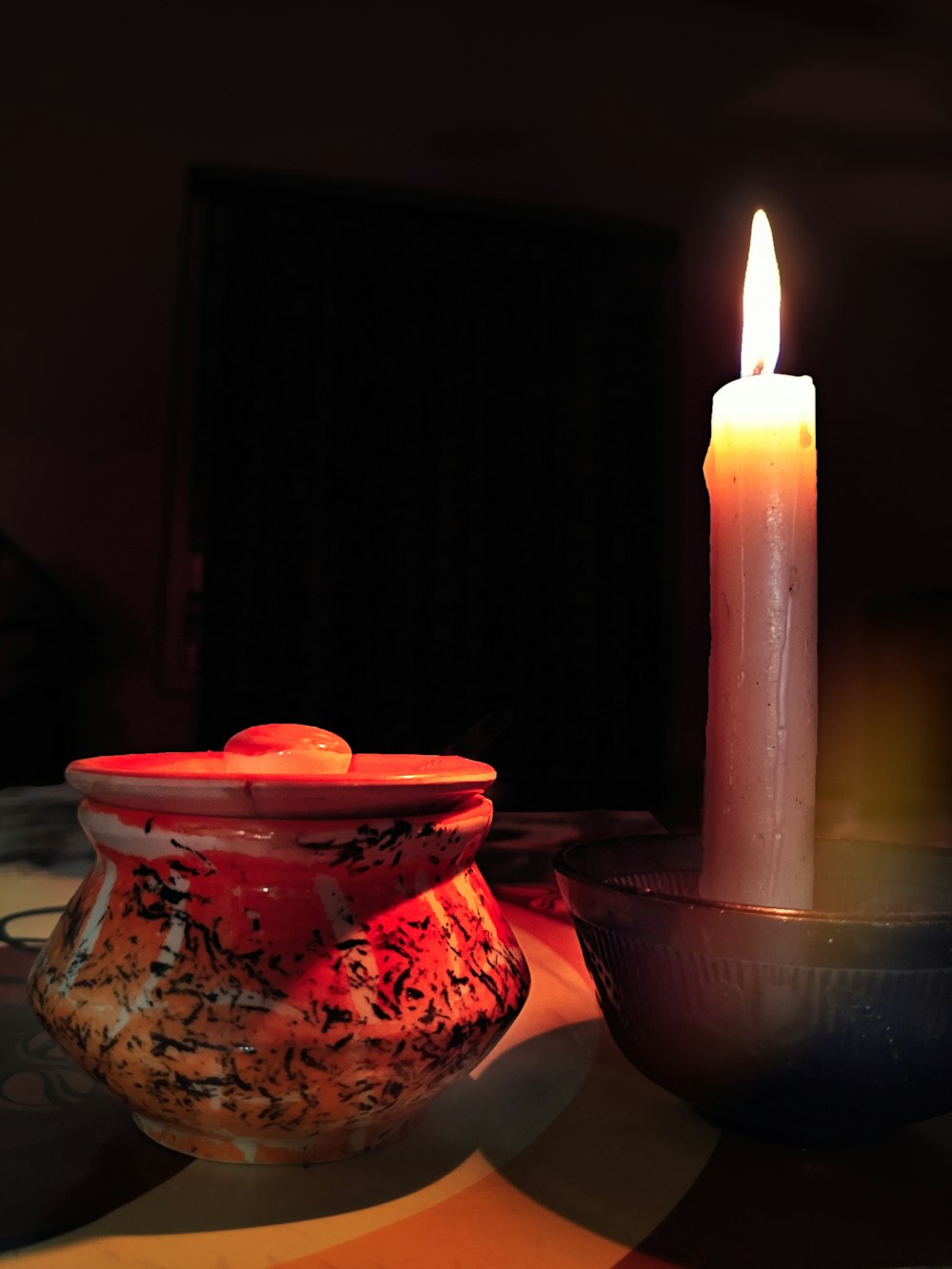 red ceramic pot beside taper candle