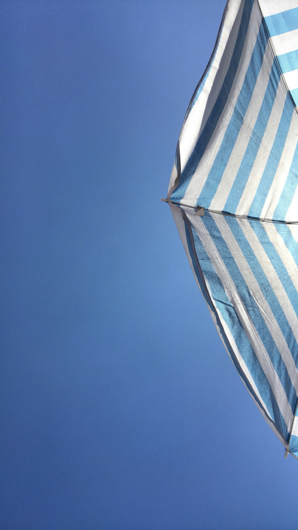 a blue and white striped umbrella against a blue sky
