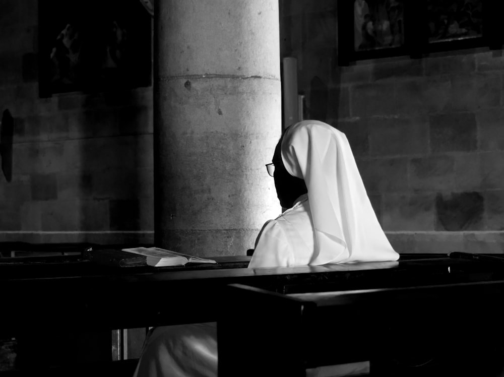 grayscale photography of woman wearing veil sitting on bench