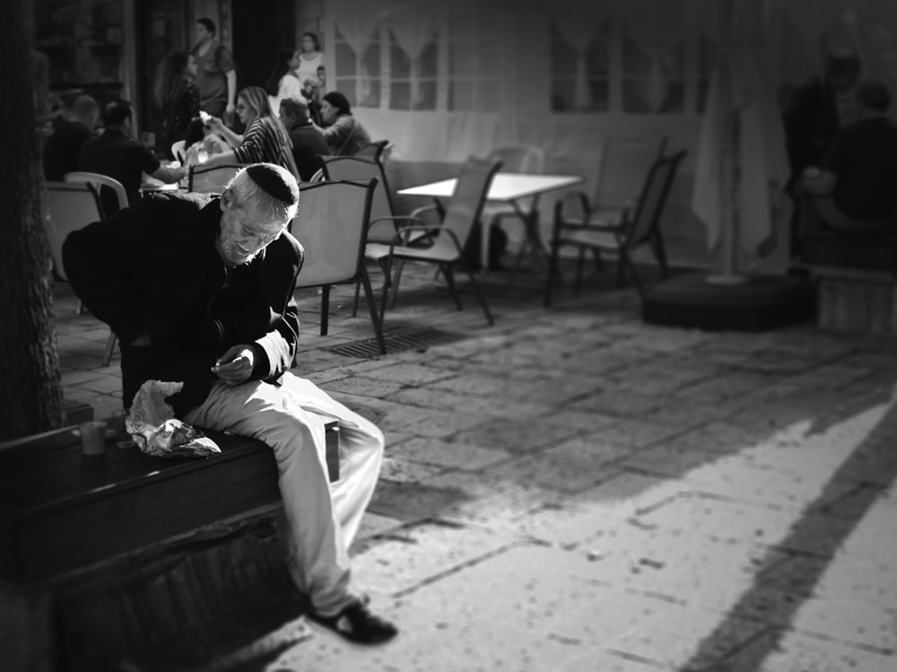 grayscale photography of man sitting outdoors