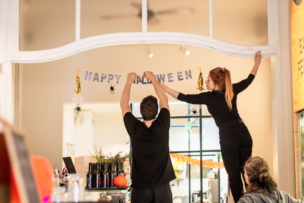 man and woman hanging Happy Halloween bunting