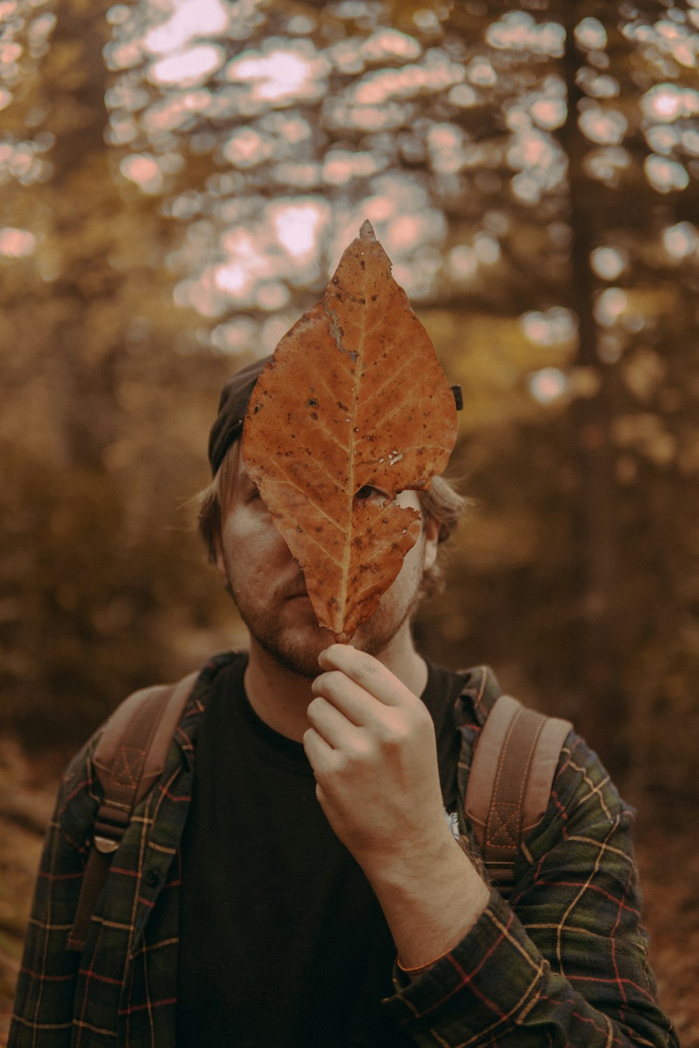 man wearing black bennies holding brown leaf