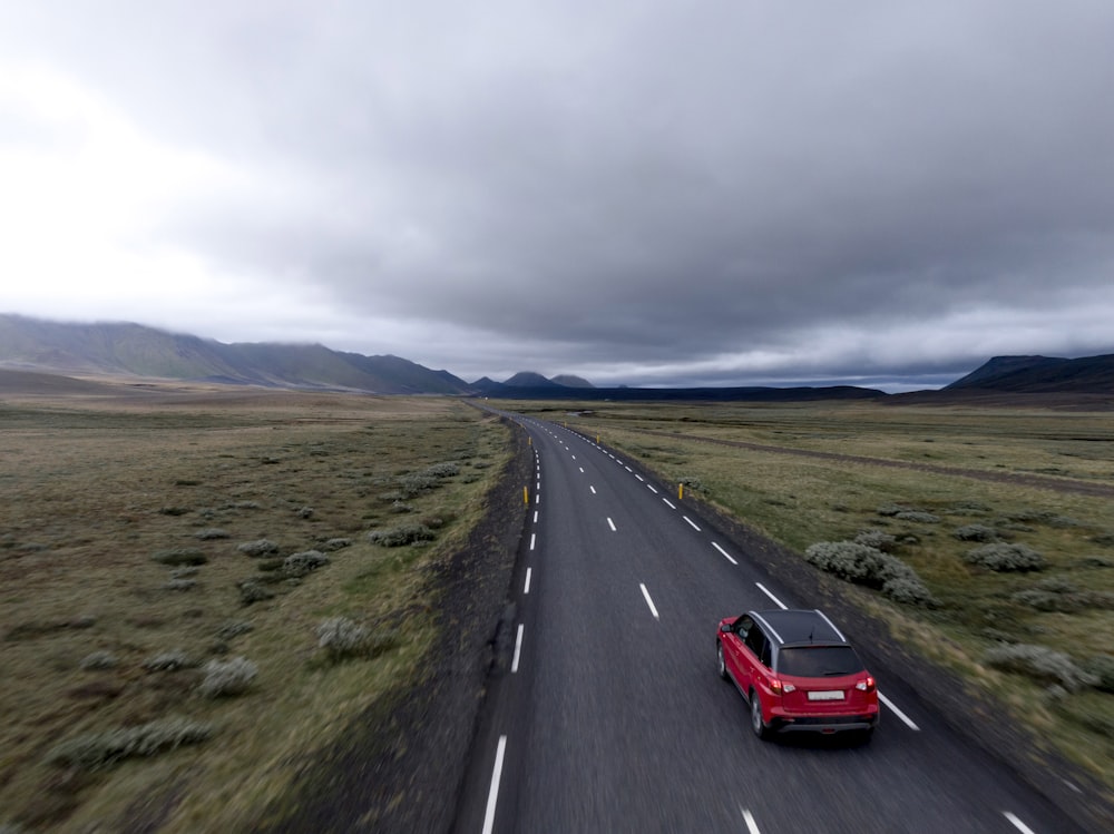 red hatchback vehicle on asphalt road