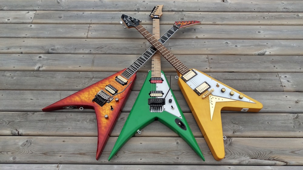 three assorted-color flying V electric guitars