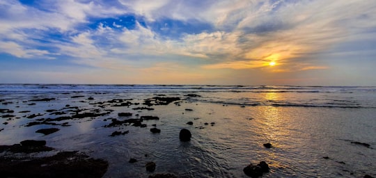 silhouette of stones and body of water under gray and white clouds in Porbandar India