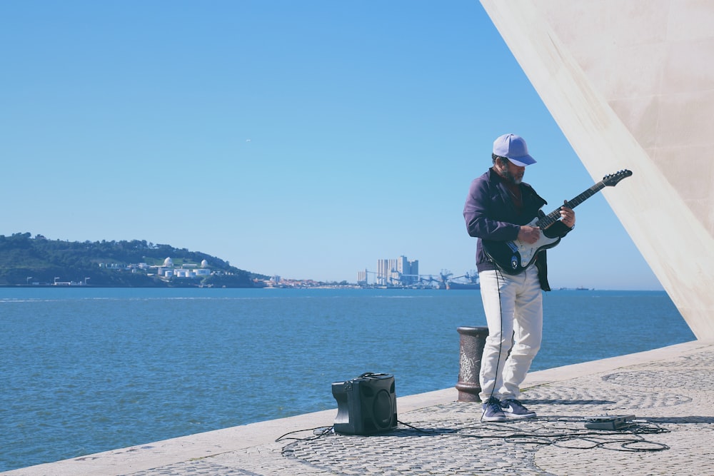 man with electric guitar near sea