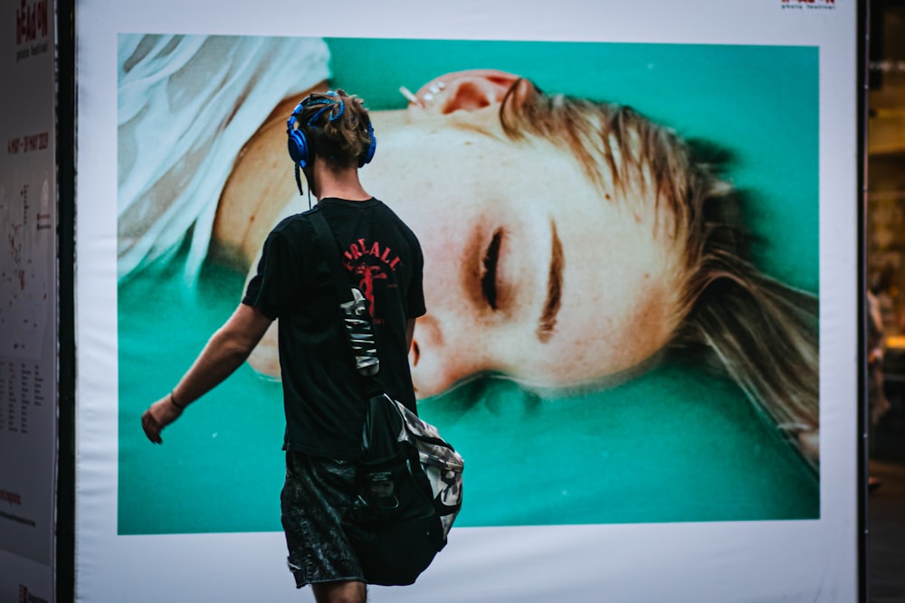 man walking beside poster