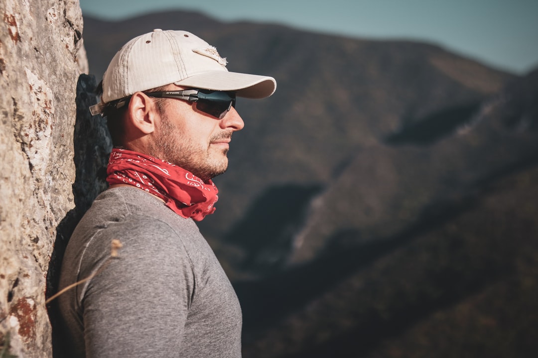 man wearing gray shirt and white cap