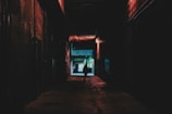 Dimly lit urban alleyway with scattered light and sharp contrasts, evoking a silent story.
