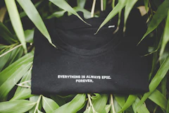 Folded black t-shirt among green leaves