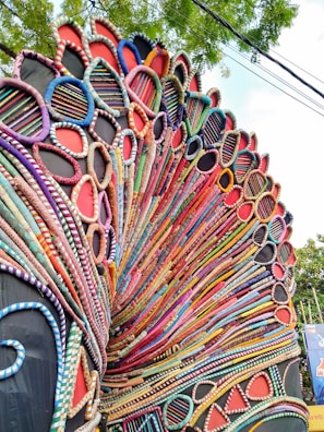 An intricate and colorful carnival costume with layered, circular patterns that resemble a peacock's feathers. The design is made up of beads and fabrics in a wide range of colors, forming a vibrant and dynamic arrangement.