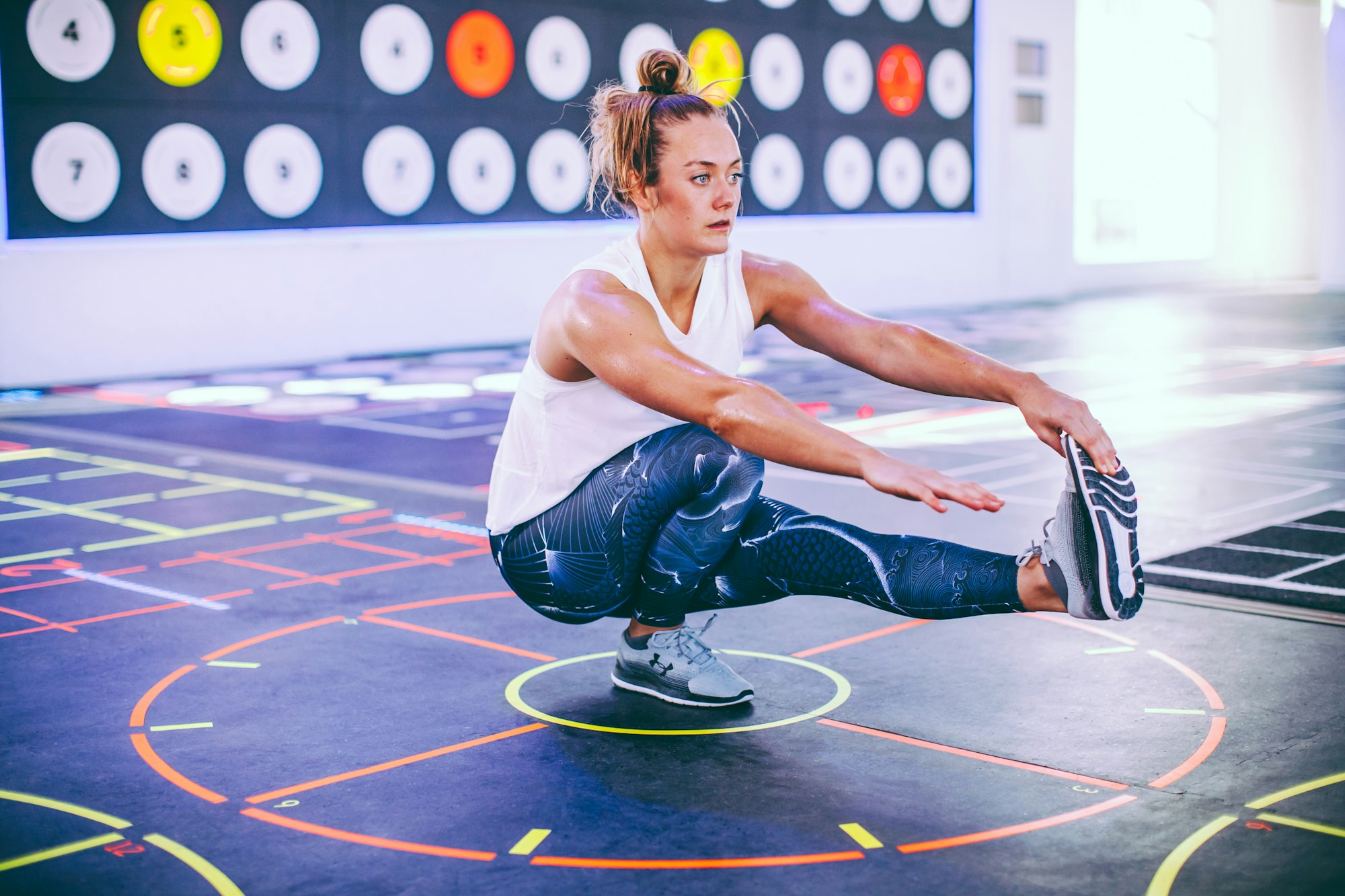 Woman doing pistol squats with floor markings in Prama