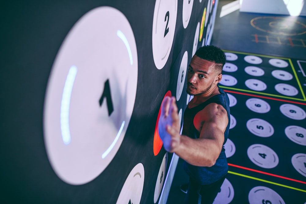 man wearing black tank top climbing and about to reach number 1