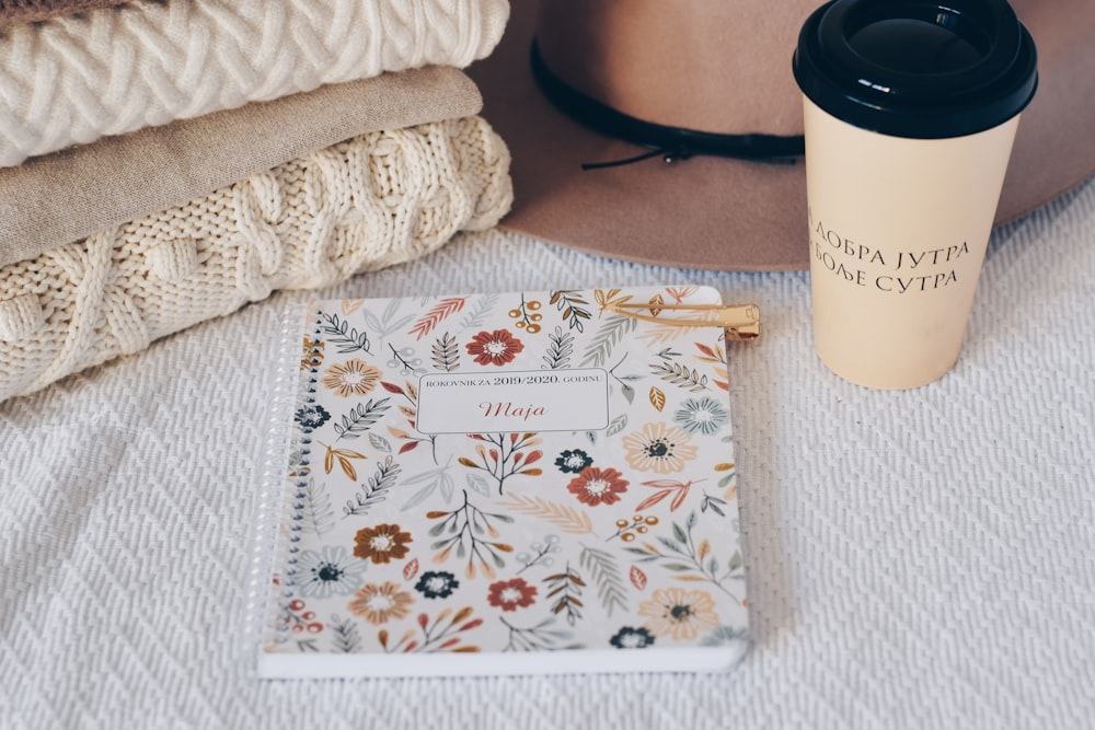 white and multicolored floral notepad by coffee cup