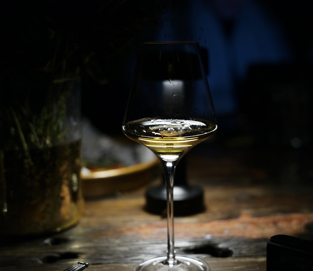 filled martini wine glass on wooden table top by desk lamp