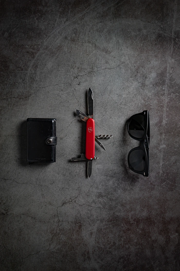 A red Swiss Army pocket knife open on a dark stone surface