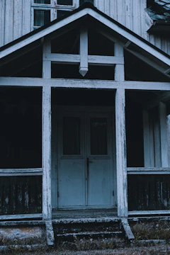 Before image of a home with old french doors and worn-out porch.