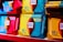 An assortment of colorful Ritter Sport chocolate packages displayed on a shelf. The packages prominently feature percentages indicating the cocoa content and are highlighted with vibrant colors such as blue, red, and yellow. The word 'NEU' is visible, suggesting a new product line.