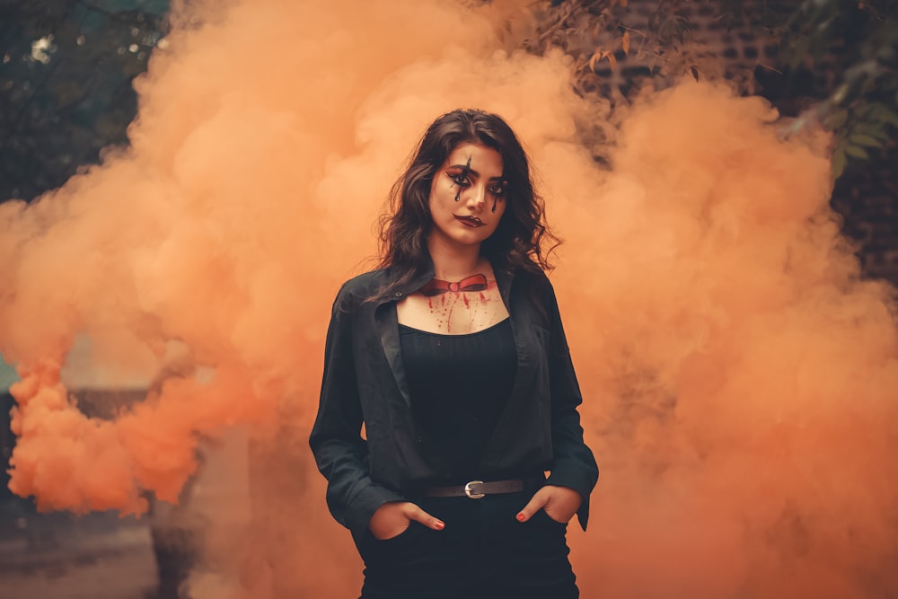 woman wearing black tank top and black jacket standing behind fog