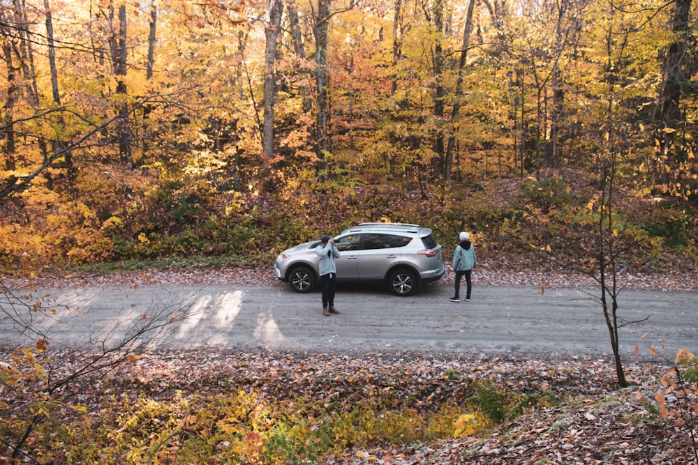 two people by a gray 5-door hatchback