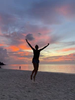 A joyful traveler capturing a sunset moment on a tropical island shore.