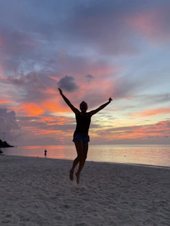 A joyful traveler capturing a sunset moment on a tropical island shore.