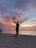 A scenic view of a traveler enjoying a sunset on a beach, capturing a moment of tranquility and joy.