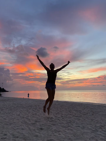 A joyful traveler snapping photos of a breathtaking sunset on a tropical beach.