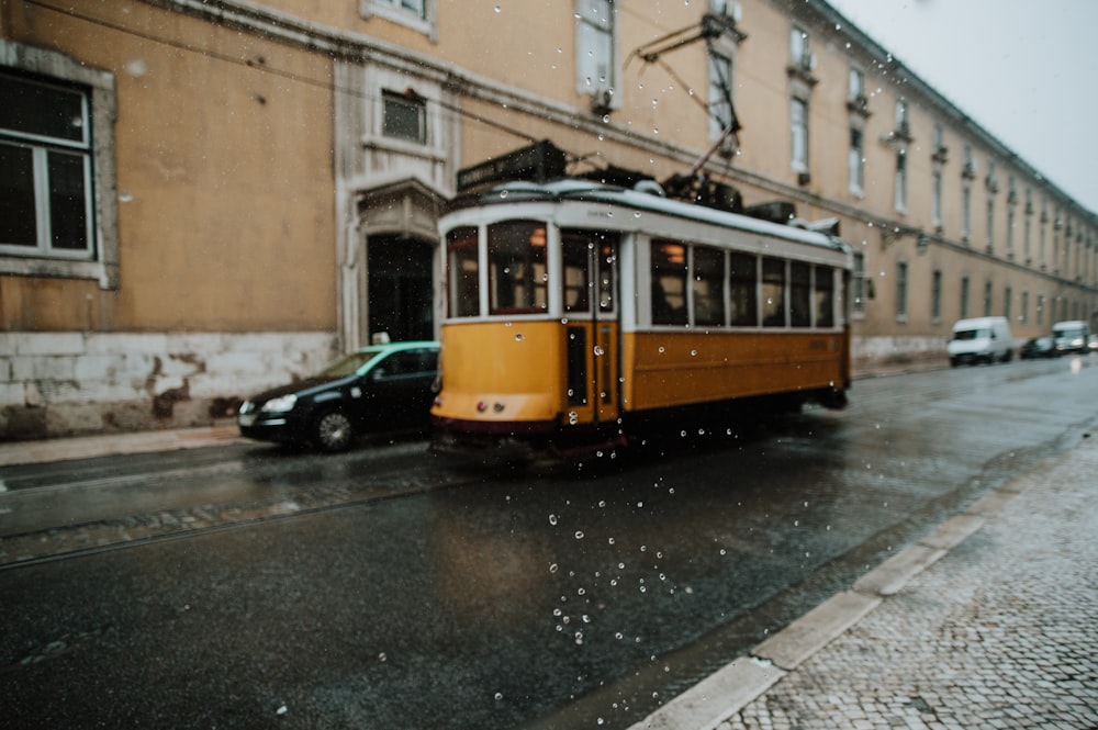 orange and white tram beside car