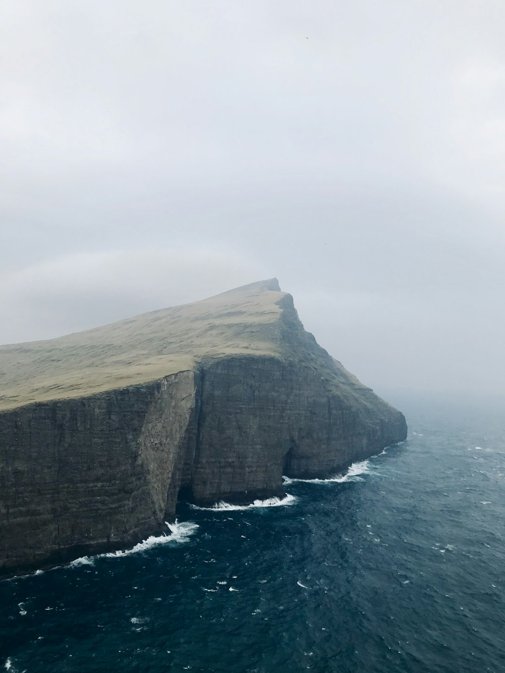 brown cliff near calm sea water during daytime