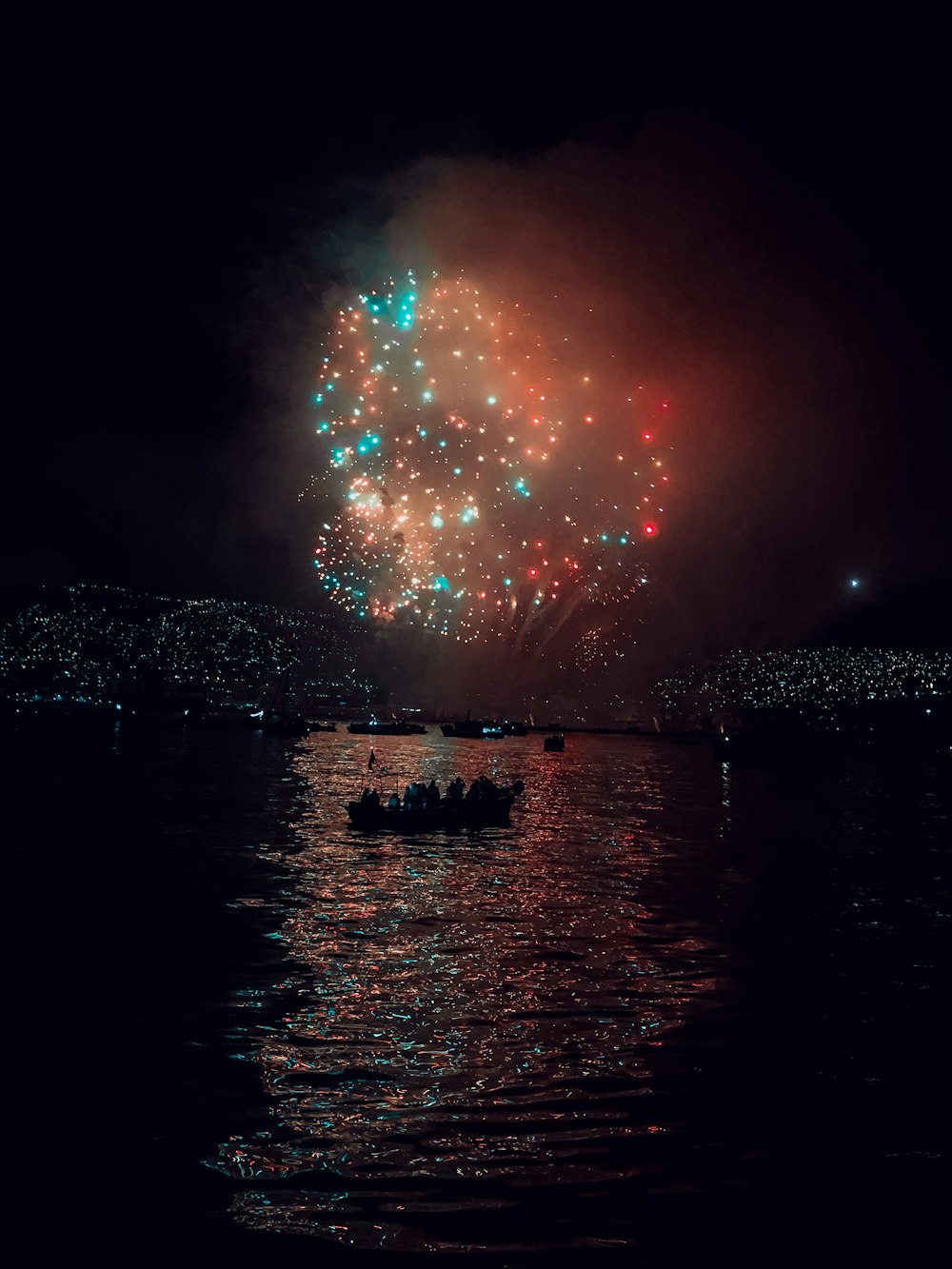 persone in barca in mare sotto fuochi d'artificio