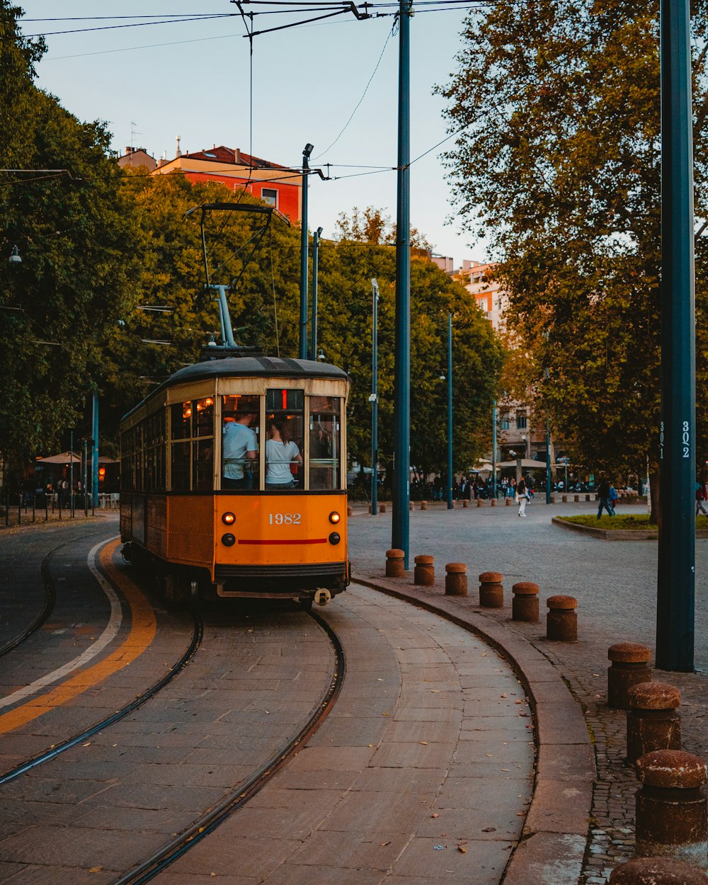 people in orange tram and other people walking on park under blue and white sky during daytime