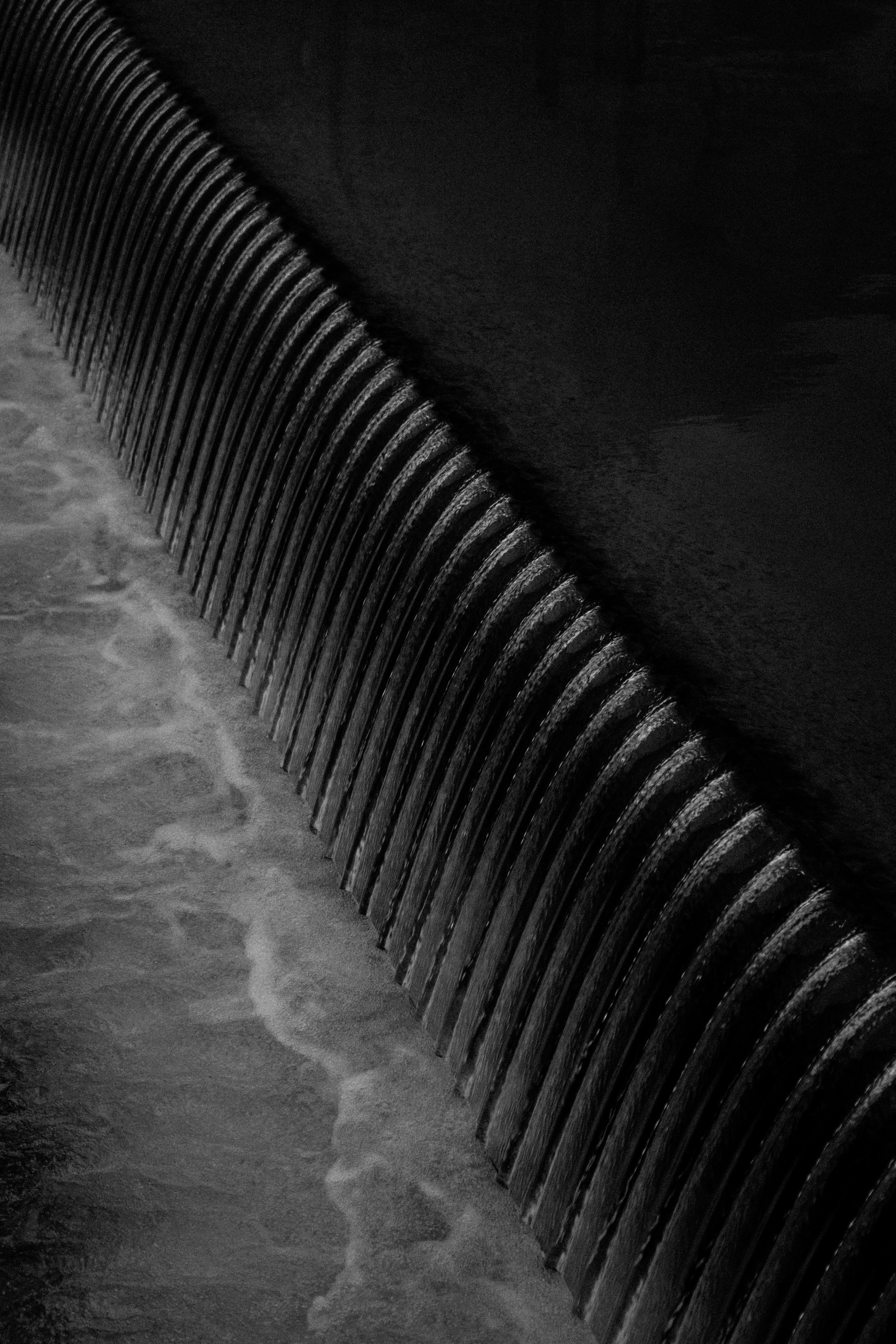 Une photo en noir et blanc de l’eau qui coule sur un mur photo Photo 락 단시 Gratuite sur Unsplash